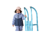 Glückliches kleines Mädchen in Winterkleidung und Mütze, das einen blauen Schlitten hält.
