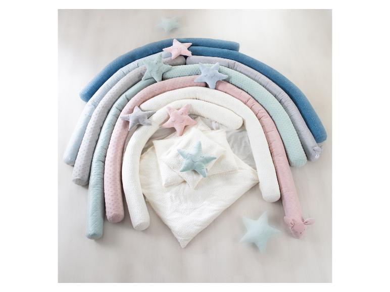 Regenbogenförmiges Babynest mit Sternenkissen und weißer Bettwäsche.