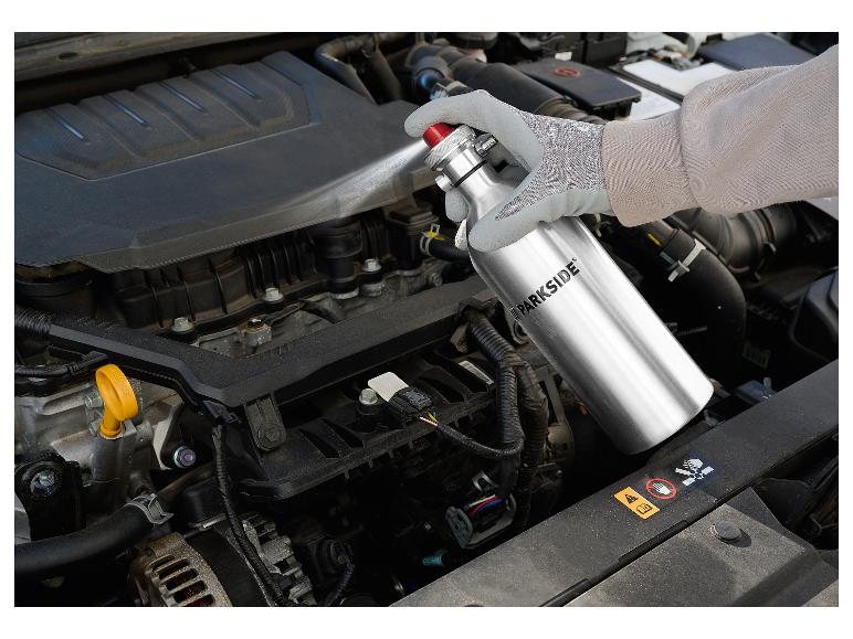 Eine Person reinigt einen Automotor mit einem Parkside-Spray.
