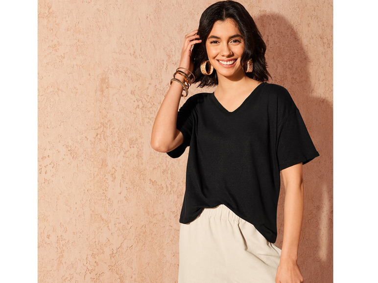 Eine Frau trägt ein schwarzes T-Shirt und eine weiße Hose.