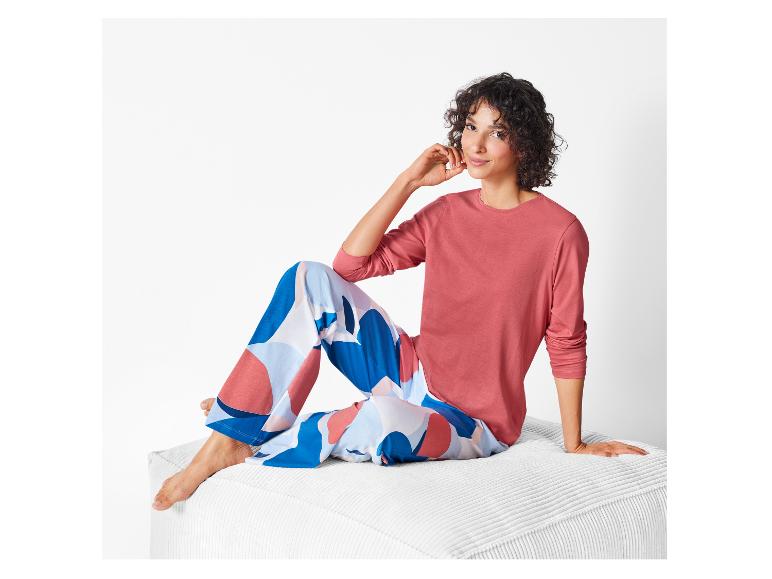 Eine Frau trägt eine rosafarbene Langarmshirt und eine Hose mit abstrakten Muster.