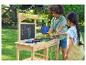 Kinder spielen mit einer hölzernen Matschküche im Garten.