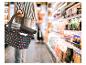 Person in gestreiftem Hemd trägt einen gepunkteten FALKO-Korb im Supermarkt.
