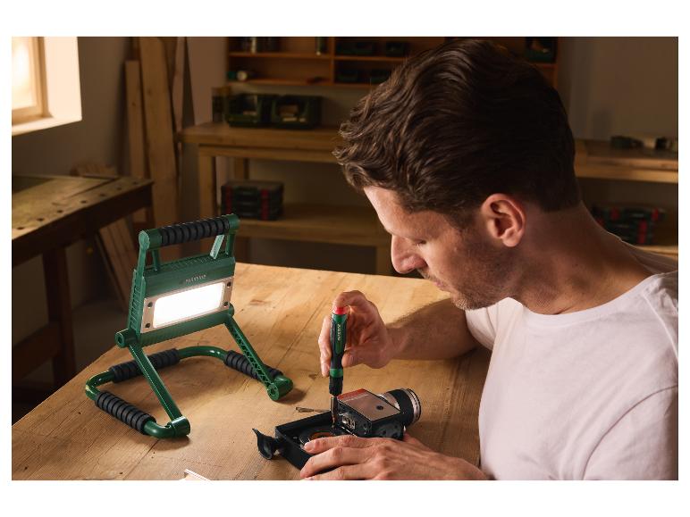 Mann arbeitet in einer Werkstatt, die vom PARKSIDE LED-Strahler beleuchtet wird.