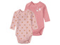 Zwei rosafarbene Babybodys mit langen Ärmeln von Lupilu, einer mit Blumenmuster und einer mit einzelnen Blumen.