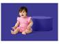 Ein Baby in einem rosa Strampler mit Sonnenmuster sitzt neben einem blauen Pouf.