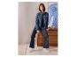 Frau in ESMARA® Wide Leg Jeans und Jeansjacke sitzt auf einer Kommode.