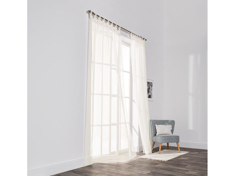 Weiße Voile-Vorhänge für ein Fenster mit einem Stuhl.