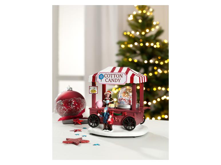 Weihnachtliche Zuckerwattewagen-Dekoration mit Figuren und roter Kugel.