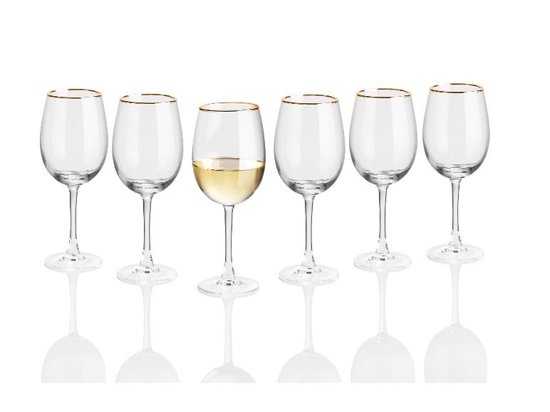 Sechs Gläser mit goldenem Rand, eines mit Weißwein gefüllt.
