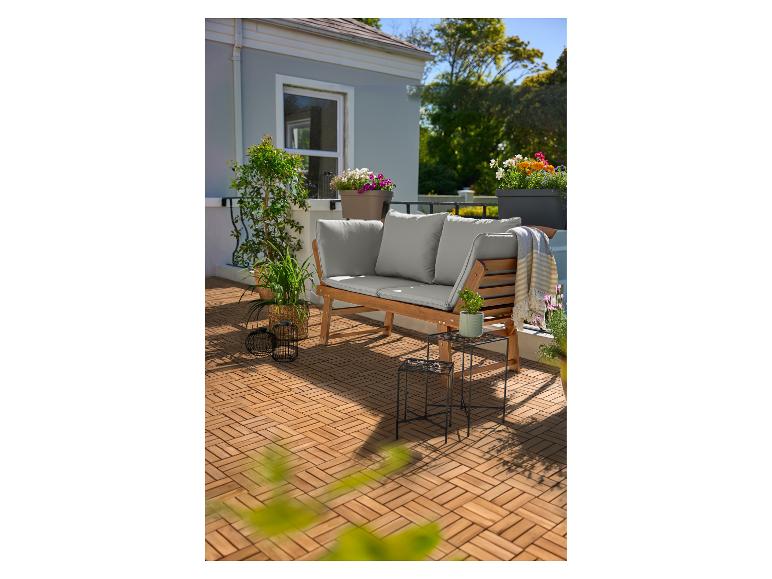 Holzterrasse mit einer Holzbank mit grauen Kissen, Pflanzen und Blumen in Töpfen.