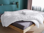 Eine weiße Bettdecke und ein Kissen auf einem Bett mit Holz-Kopfteil.
