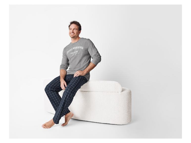 Mann entspannt im karierten Pyjama mit Langarmshirt.
