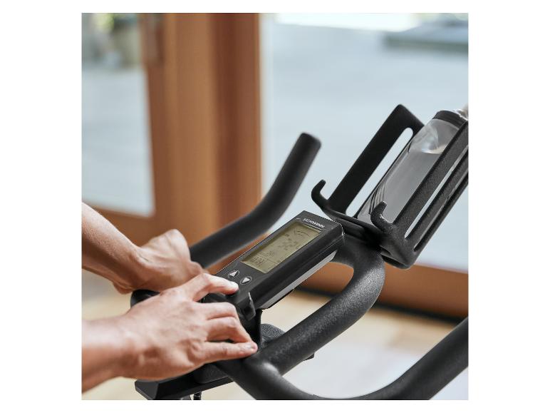 Person stellt das Bedienfeld eines Schwinn Heimtrainers mit Flaschenhalter ein.