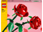 Zwei rote Spielzeugrosen mit grünen Stielen auf rosa Hintergrund, mit Kartondetails.