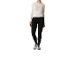 Frau in weißem Langarmshirt und schwarzen Sportleggings mit Sportschuhen.