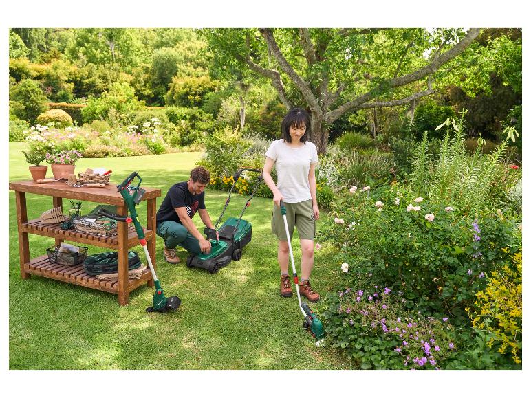 Paar im Garten mit Rasenmäher, Trimmer und Gartentisch mit Werkzeugen.