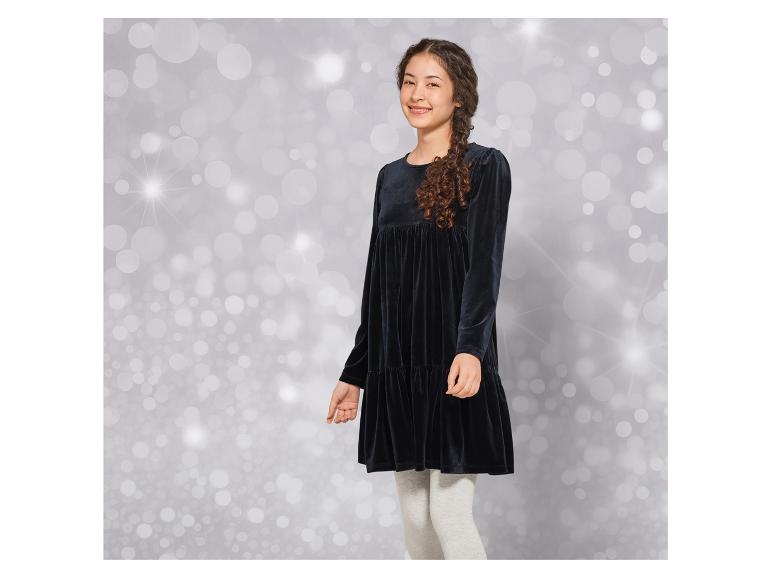 Ein Mädchen trägt ein schwarzes Samtkleid mit grauen Leggings.