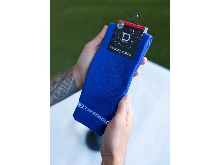 Männerhände halten blaue Tapedesign Fußballsocken mit Etikett.