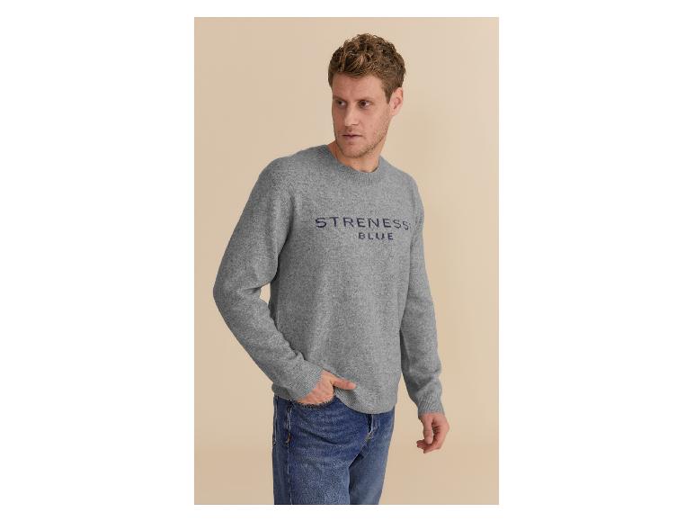 Mann in grauem Pullover mit 'STRENESS BLUE' Logo und blauen Jeans.