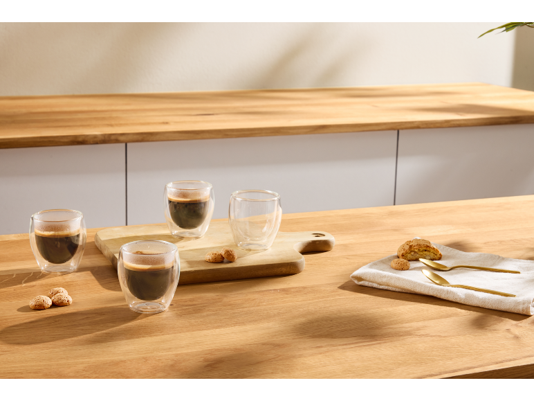 Doppelwandige Espresso-Gläser mit Keksen auf einem Holztisch.