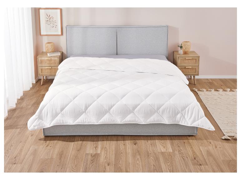 Weiße Daunendecke auf einem Bett in einem hellen Schlafzimmer.