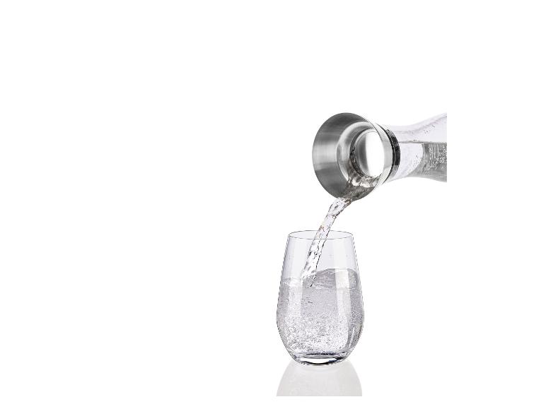Wasser wird aus einer Karaffe in ein Glas gegossen.