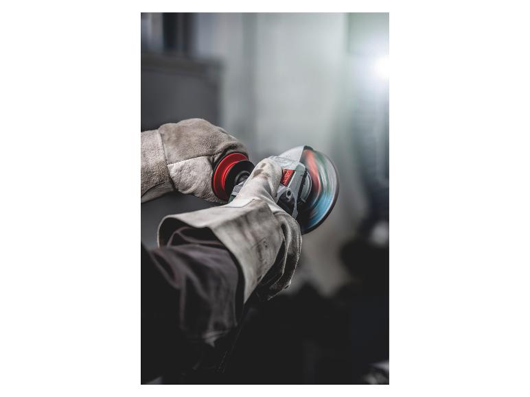 Behandschuhte Hände halten einen Winkelschleifer mit einer rotierenden Trennscheibe.