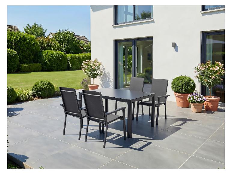 Gartenmöbel-Set mit Tisch und Stühlen auf einer Terrasse vor einem Haus mit Garten.