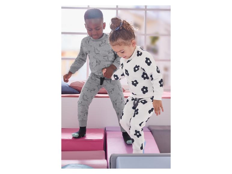 Zwei Kinder spielen auf weichen Blöcken, tragen bedruckte Pyjamas.