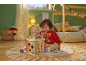 Kleinkind spielt mit einem Holz-Motorikwürfel in einem weihnachtlich dekorierten Kinderzimmer.