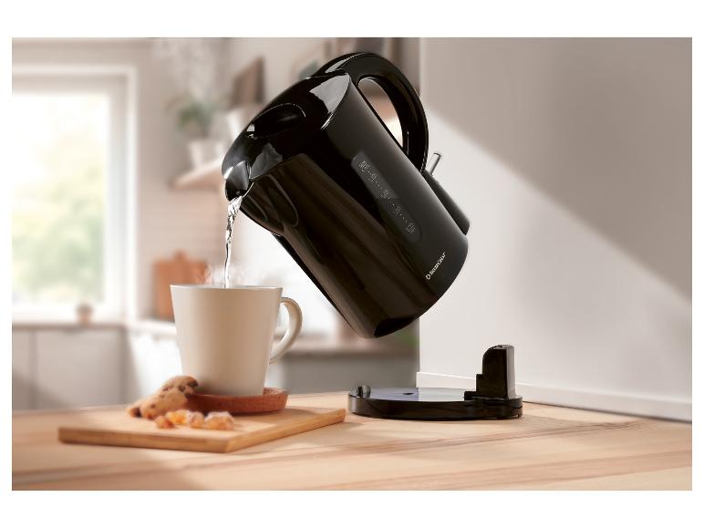 Ein SilverCrest Wasserkocher gießt heißes Wasser in eine Tasse auf einem Holztisch.