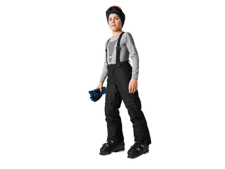 Ein junger Junge in Skiausrüstung, bestehend aus Skihose, Thermoshirt, Mütze und Skibrille.