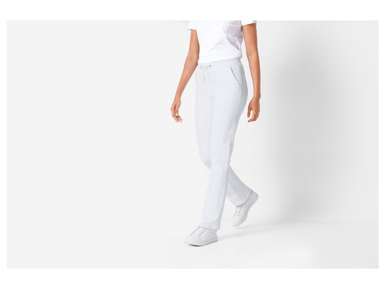 Frau in weißem T-Shirt und weißer Jogginghose mit weißen Turnschuhen.