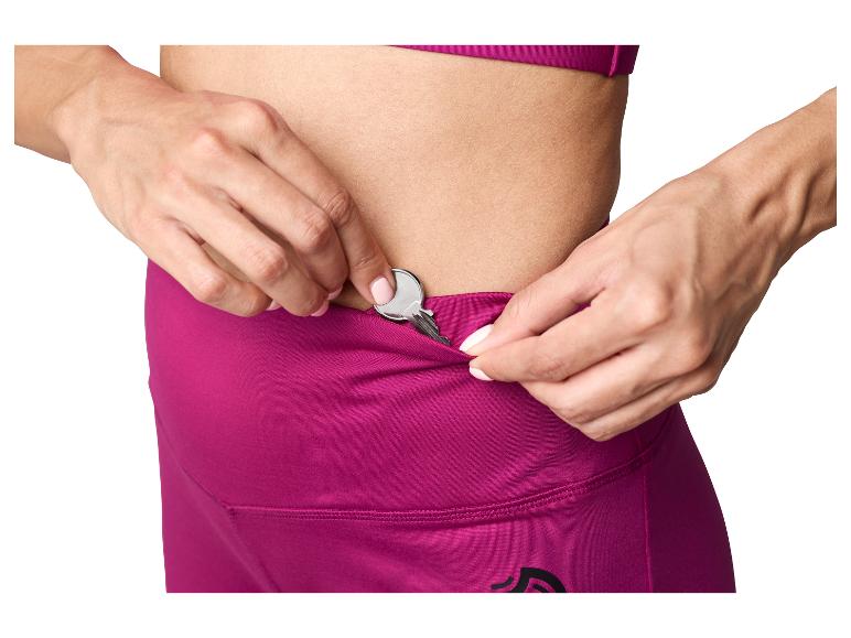 Frau steckt einen Schlüssel in die versteckte Tasche ihrer magenta Sportleggings.