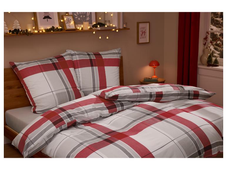 Schlafzimmer mit rot-weiß karierter Bettwäsche, Weihnachtsbeleuchtung und Dekorationen.