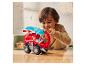 Ein Kind spielt mit einem roten Paw Patrol Spielzeuglastwagen auf einem Holztisch.