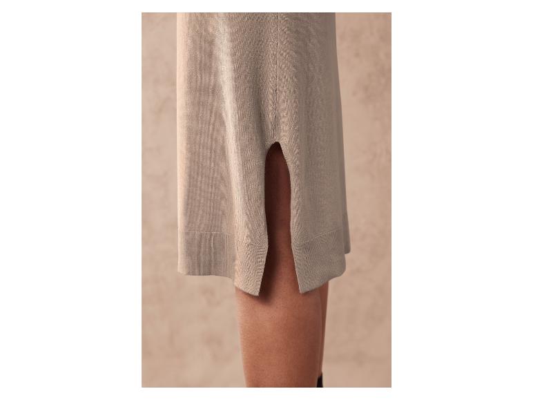 Ein beiges Strickkleid mit seitlichem Schlitz.