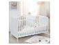 Weißes Babybett in einem hellen Kinderzimmer mit maritimen Dekorationen und Spielzeug.