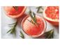 Grapefruit-Sorbet mit Rosmarin, umgeben von Grapefruithälften und Rosmarinzweigen.