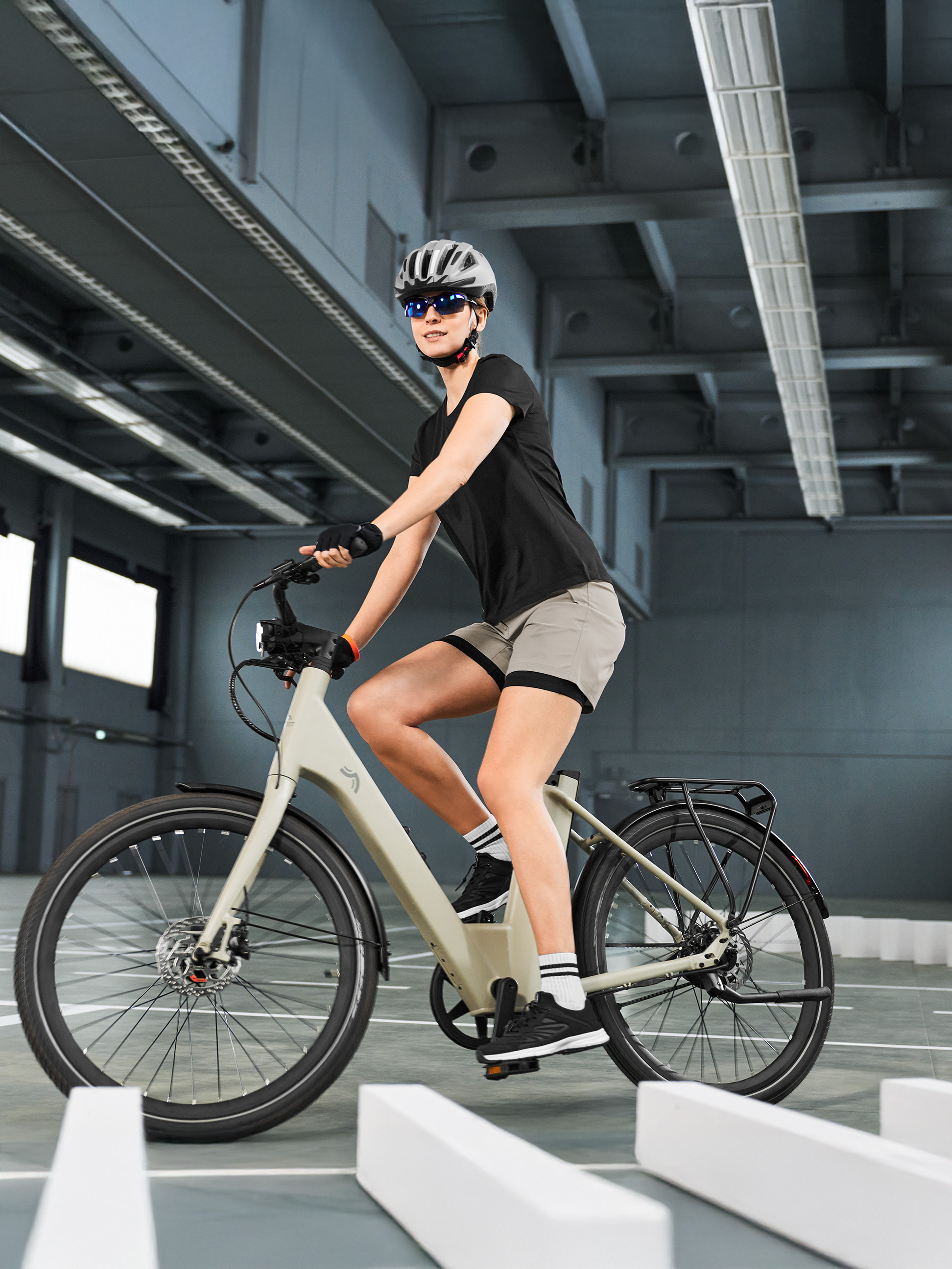 Frau in Radsportkleidung auf einem E-Bike, navigiert auf einem Indoor-Parcours.
