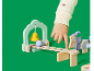 Kinderhand spielt mit einem Holzglocken- und Kugelbahnspielzeug auf grünem Hintergrund.