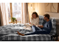 Paar genießt Frühstück im Bett mit karierter Bettwäsche.
