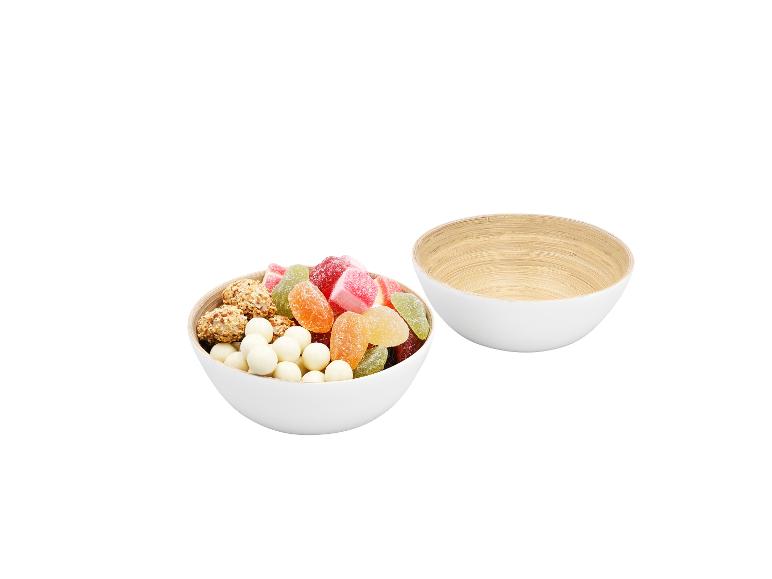 Zwei weiße Schalen, eine gefüllt mit bunten Süßigkeiten und Snacks, die andere leer.
