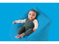Glückliches Baby in einem grünen Strickstrampler sitzt auf einem blauen flauschigen Sitzsack.