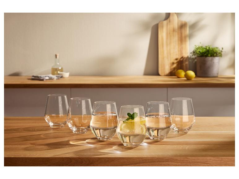 Sechs Wassergläser auf einem Holztisch, eines mit Zitrone und Minze.