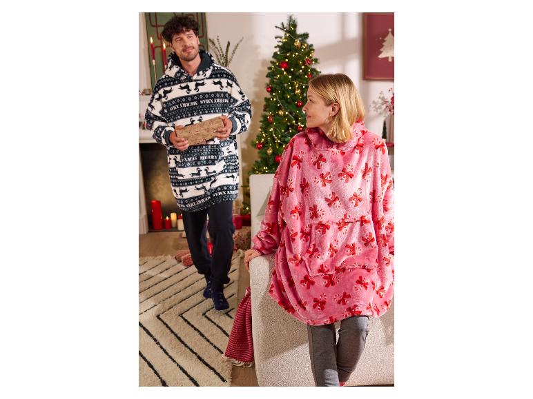 Zwei Personen tragen übergroße Weihnachtsdecken, eine hält ein Geschenk.