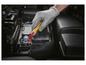 Eine Hand in einem Schutzhandschuh verwendet einen isolierten Schraubendreher, um die Autobatterie zu lösen.