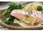 Lachs mit Brokkoli, Kartoffeln und Zitrone auf einem grünen Teller.