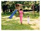 Mutter und Tochter spielen auf einem Spielplatz mit Rutsche und Schaukeln.